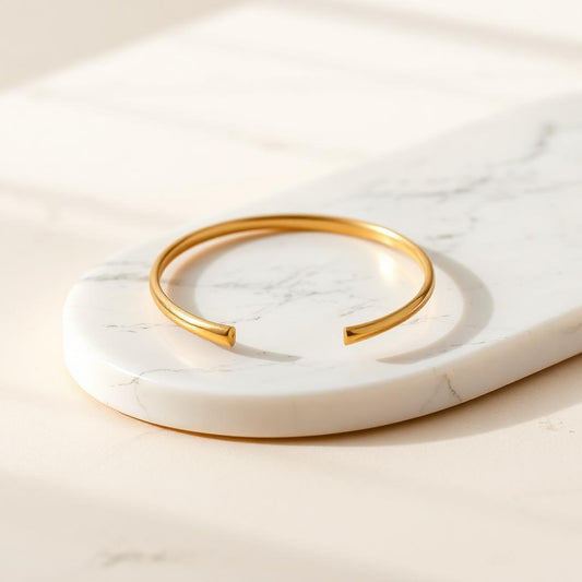 Yellow gold slim stacking cuff on warm marble