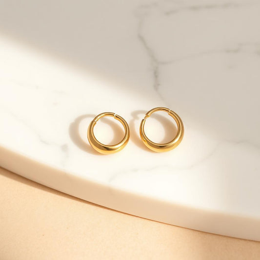 Yellow gold dome hoops on warm marble