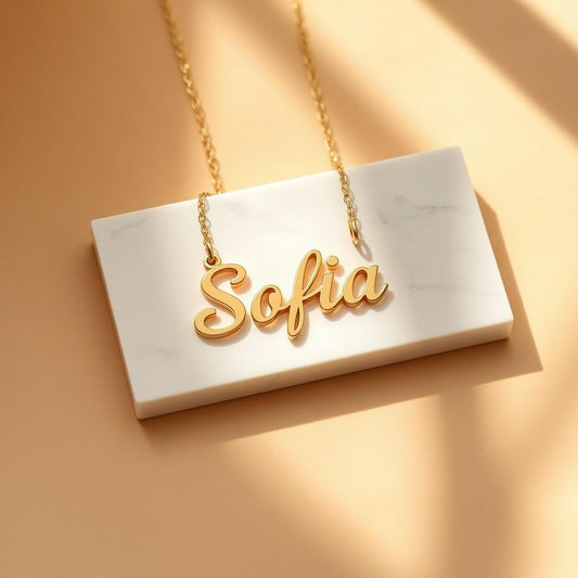 Script name necklace in yellow gold on warm marble
