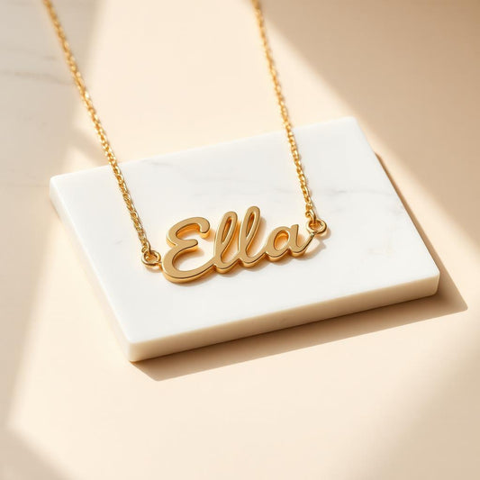 Paperclip chain name necklace in yellow gold on warm marble