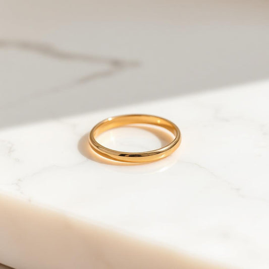 Yellow gold slim stacking band ring on warm marble