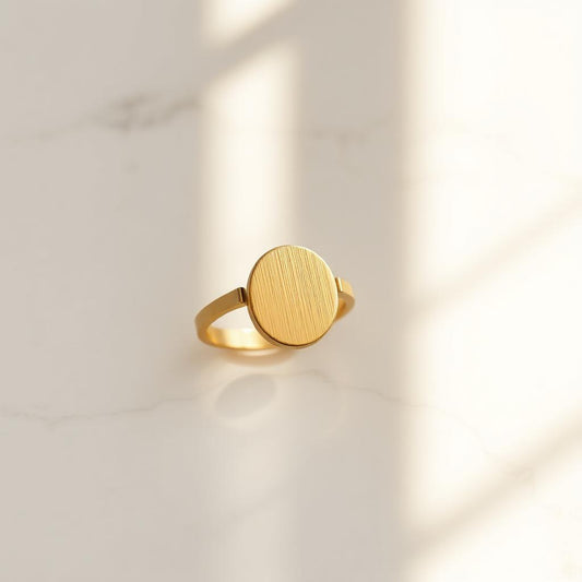 Yellow gold oval signet ring on warm marble