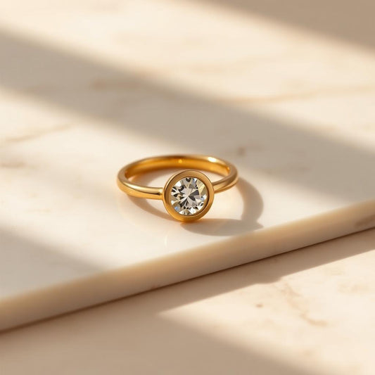 Yellow gold bezel solitaire ring on warm marble